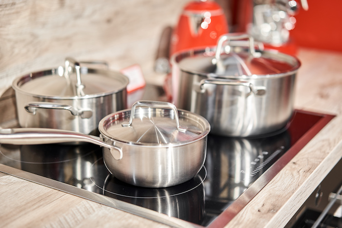 New cookware set on black induction hob in modern kitchen. Pot and frying pan in the kitchen on the hob. cooking concept - close up of kitchen table with modern equipment